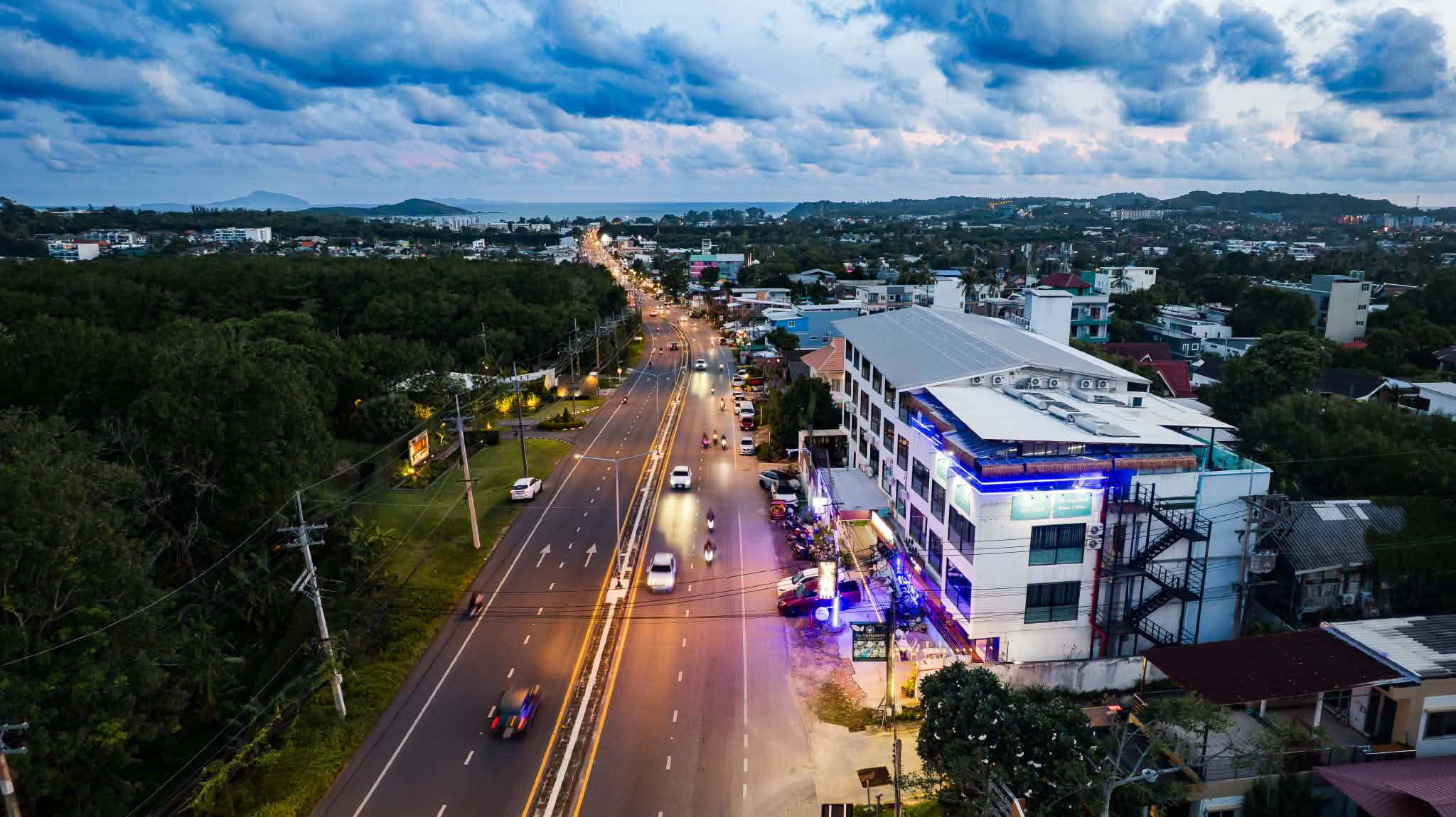 Dusk aerial of De Blue Sea Rawai Hotel with Wiset Road heading to the sea